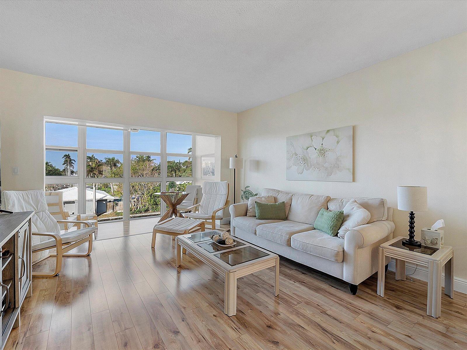 A living room features light wood flooring, a beige sofa, and large windows with outdoor views — 1481 S Ocean Boulevard # 315a, Pompano Beach FL 33062, POMPANO BEACH, FL