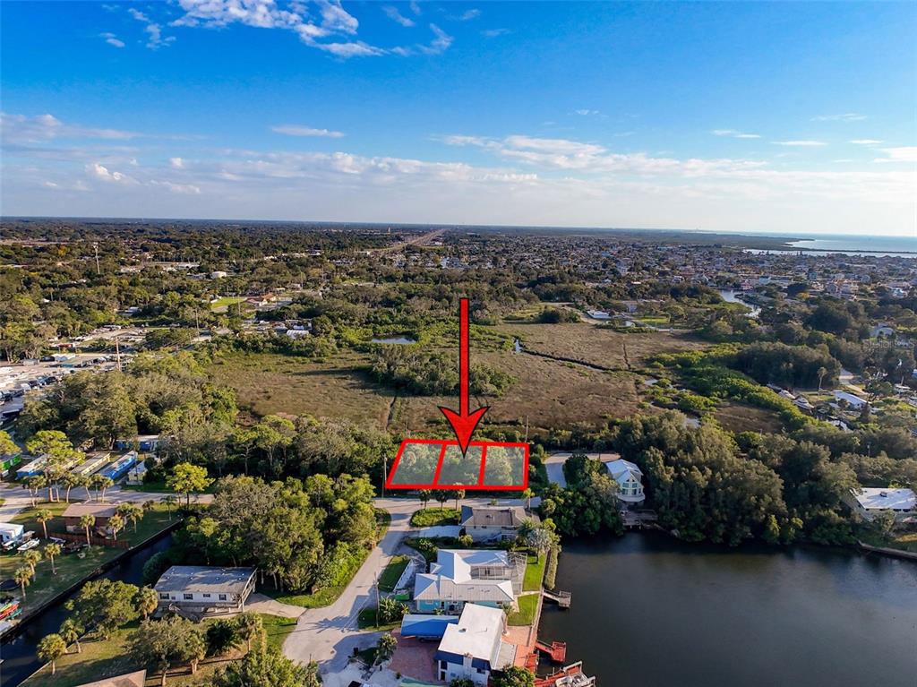 An aerial view shows a vacant, rectangular lot outlined in red near a waterfront neighborhood — lot 11 NOWIKI AVENUE, HUDSON, FL
