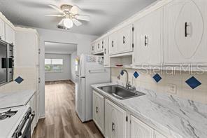 A kitchen features white cabinets, marble-patterned countertops, a stainless steel sink, and wood-look flooring — 5257 81ST LANE N UNIT 17, ST PETERSBURG, FL