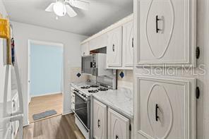 A kitchen features white cabinets, a stainless steel stove, and a doorway leading to another room — 5257 81ST LANE N UNIT 17, ST PETERSBURG, FL