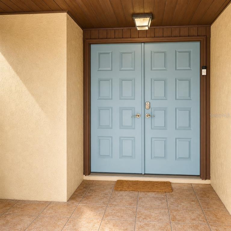 A light blue double front door with rectangular panels sits under a covered entryway — 612 WOOD DRIVE, KISSIMMEE, FL