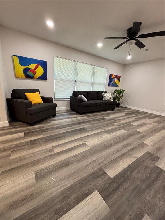 A living room features dark gray furniture, wood-look flooring, and a ceiling fan — 612 WOOD DRIVE, KISSIMMEE, FL