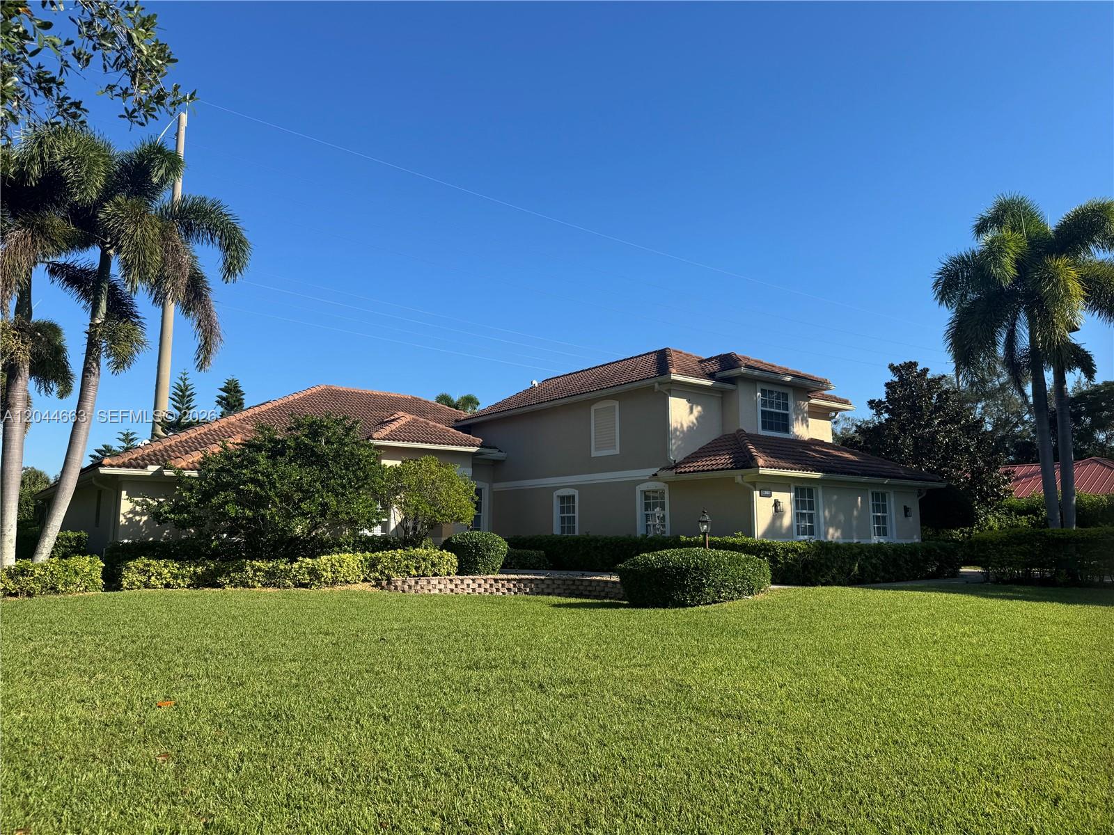 A two-story house with a tile roof and palm trees sits behind a large lawn — 5220 Rosewood Ln, Vero Beach FL 32966, VERO BEACH, FL