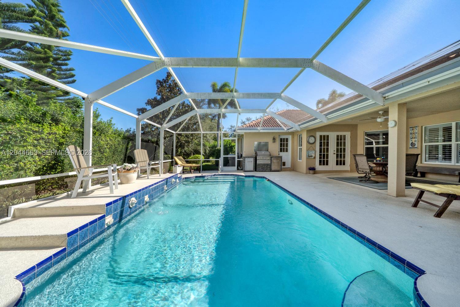A rectangular swimming pool is enclosed by a screened lanai with a patio area — 5220 Rosewood Ln, Vero Beach FL 32966, VERO BEACH, FL
