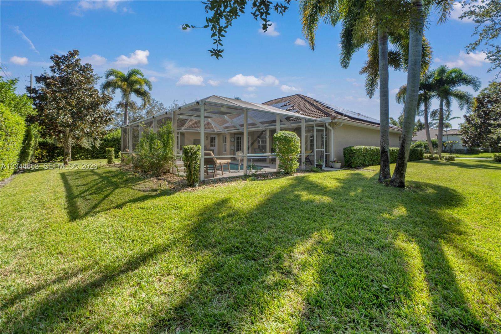 A backyard features a screened-in pool enclosure, palm trees, and a manicured lawn — 5220 Rosewood Ln, Vero Beach FL 32966, VERO BEACH, FL
