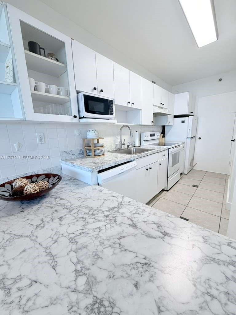 A kitchen features white cabinets, marble-patterned countertops, and stainless steel appliances — 100 Lincoln Rd # 1220, Miami Beach FL 33139, MIAMI BEACH, FL