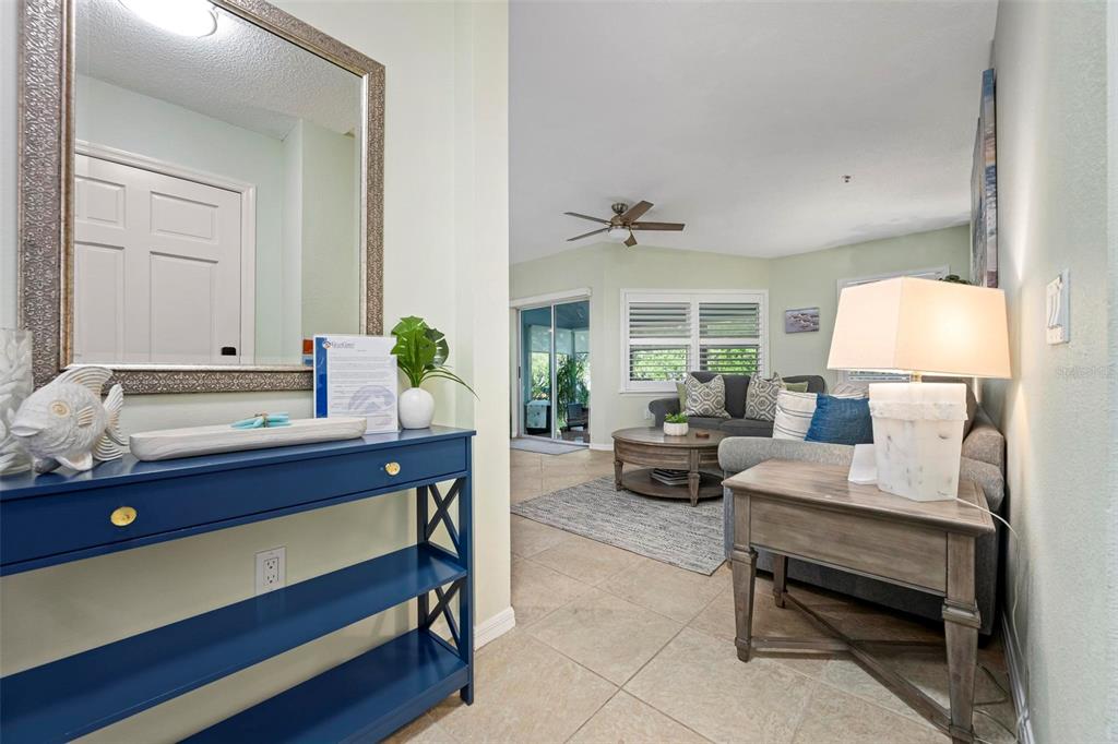 A blue console table sits in a foyer leading to a living room with tile floors — 1269 SIESTA BAYSIDE DRIVE UNIT 1269C, SARASOTA, FL