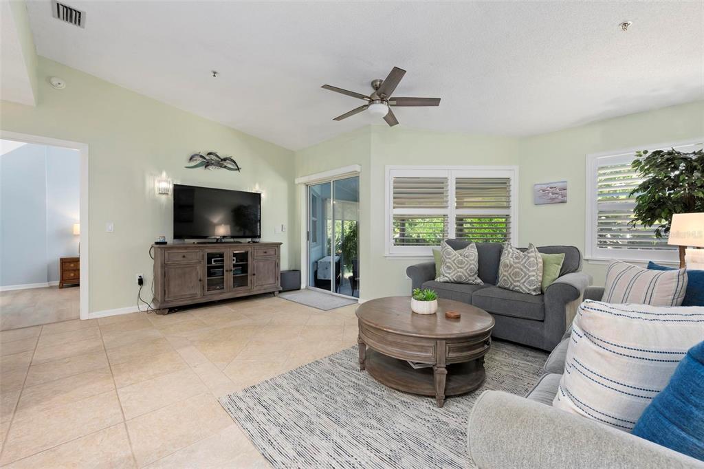 A living room features tile floors, a ceiling fan, a television console, and gray sofas — 1269 SIESTA BAYSIDE DRIVE UNIT 1269C, SARASOTA, FL