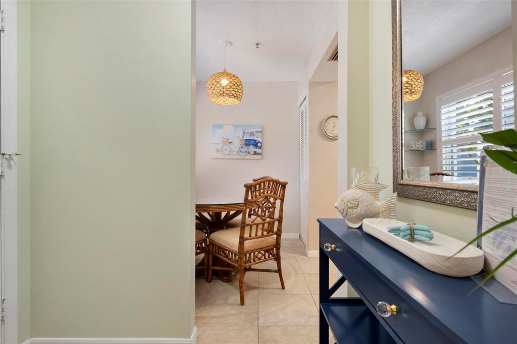 A view from a hallway into a dining area with a rattan chair and table — 1269 SIESTA BAYSIDE DRIVE UNIT 1269C, SARASOTA, FL