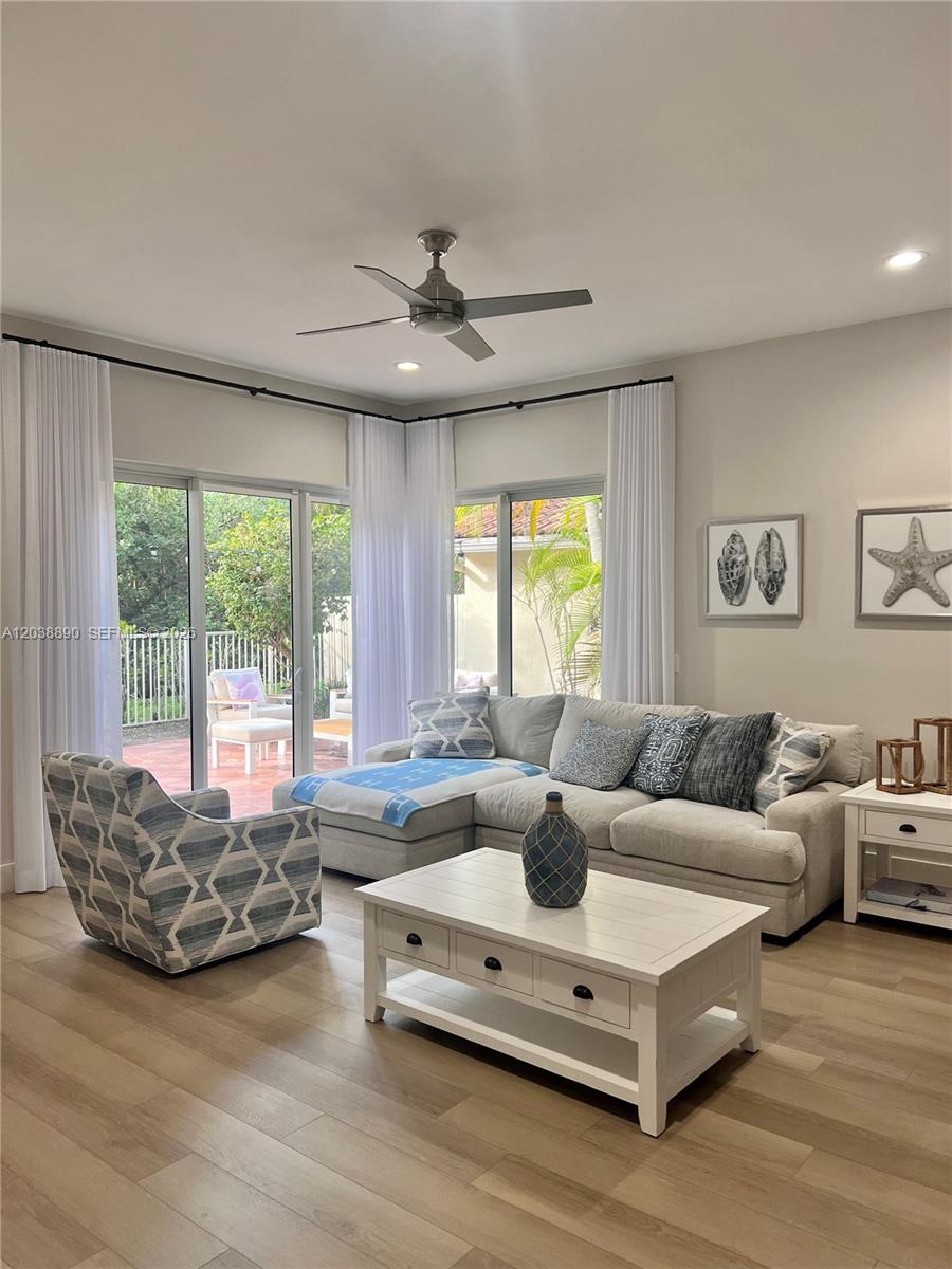 A living room features a sectional sofa, patterned armchair, white coffee table, and sliding glass doors — 1480 Sweetbay Way, Hollywood FL 33019, HOLLYWOOD, FL