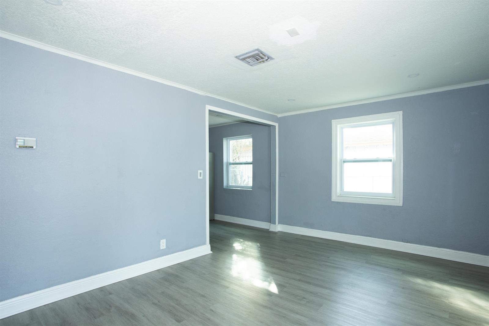 A room with light blue walls, gray wood-look flooring, and a doorway to another room — 849 W 2nd Street # B, Riviera Beach FL 33404, RIVIERA BEACH, FL