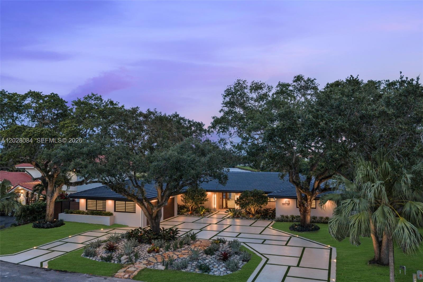 A modern single-story house features a geometric paved driveway and large oak trees at dusk — 4220 Casper Ct, Hollywood FL 33021, HOLLYWOOD, FL