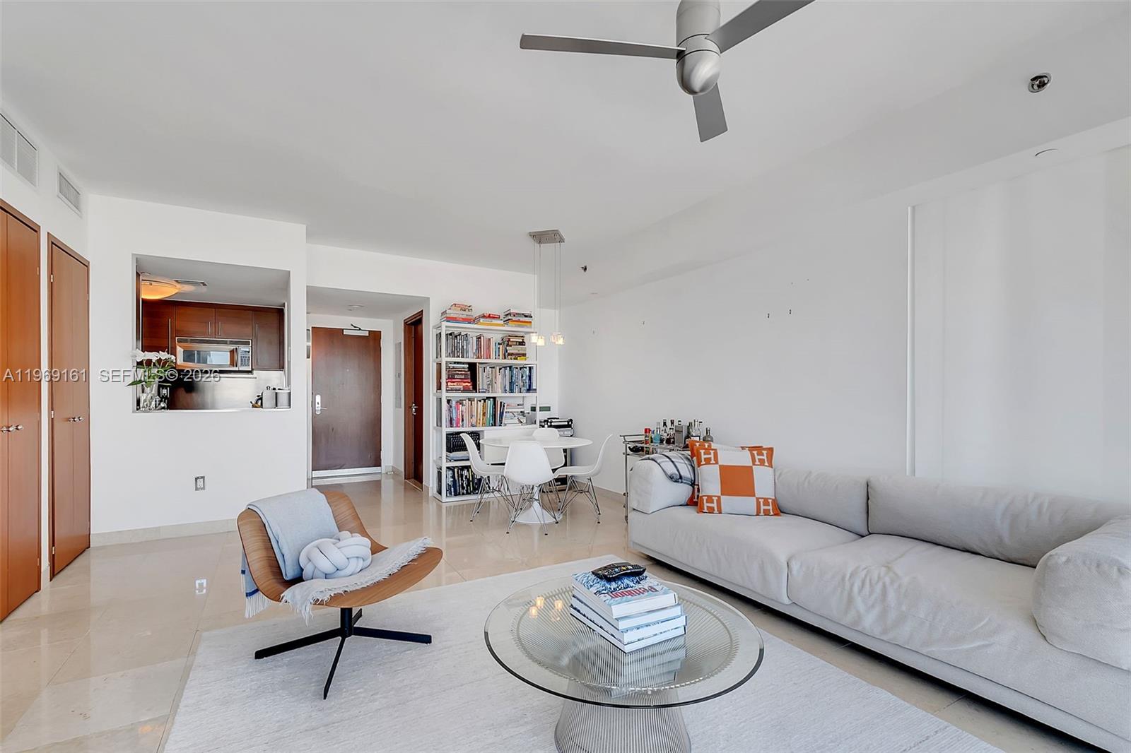 A modern living room features a white sofa, glass coffee table, and a dining area — 450 Alton Rd # 3208, Miami Beach FL 33139, MIAMI BEACH, FL