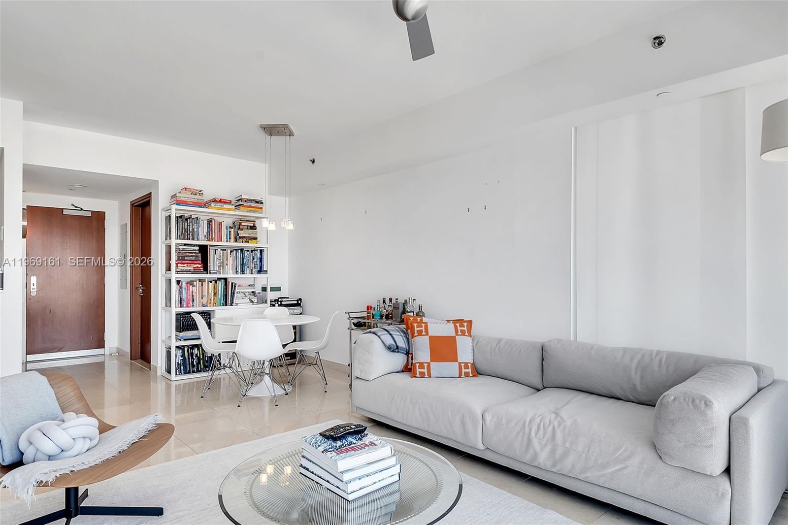 A bright living room features a grey sofa, a glass coffee table, and a dining area — 450 Alton Rd # 3208, Miami Beach FL 33139, MIAMI BEACH, FL