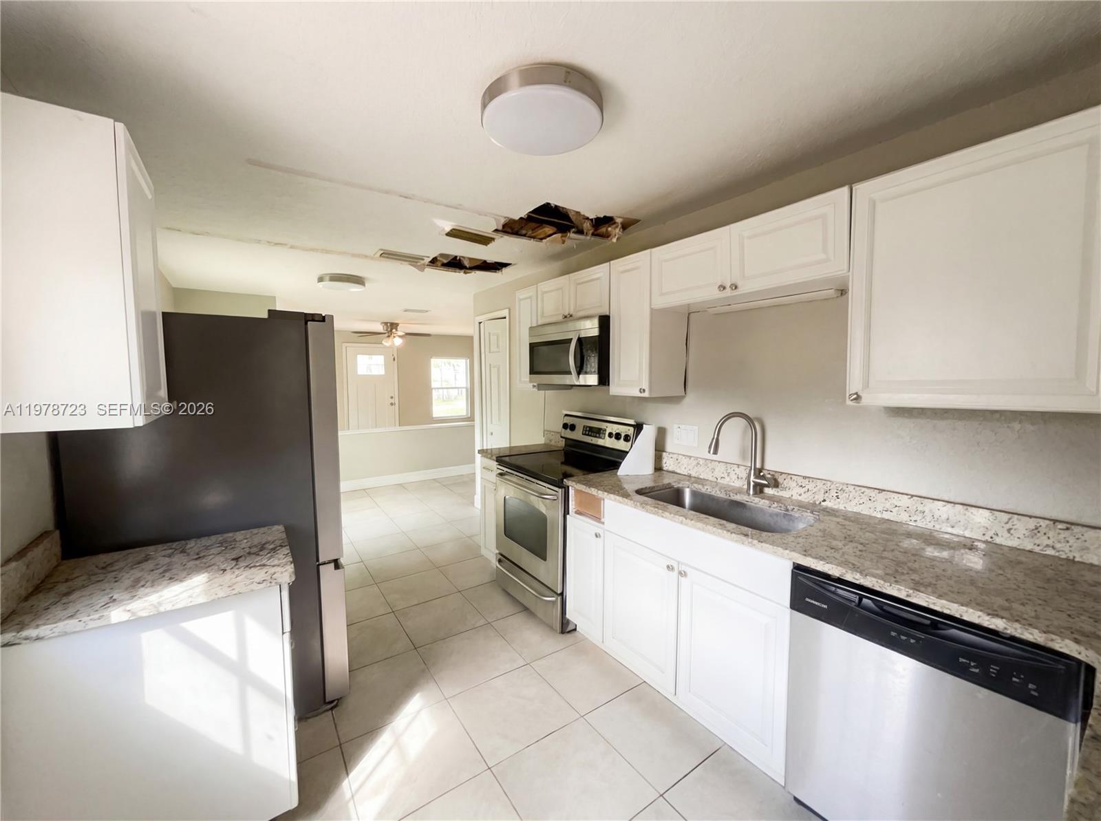 A kitchen features white cabinets, granite countertops, stainless steel appliances, and damaged ceiling drywall — 244 S Rhodes, Mount Dora FL 32757, MOUNT DORA, FL