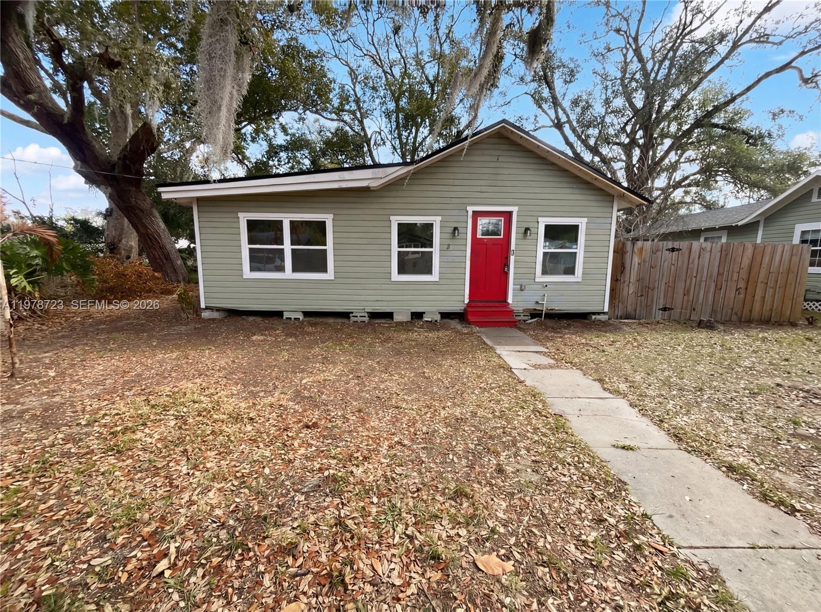 A single-story house with light green siding and a red front door sits outdoors — 244 S Rhodes, Mount Dora FL 32757, MOUNT DORA, FL