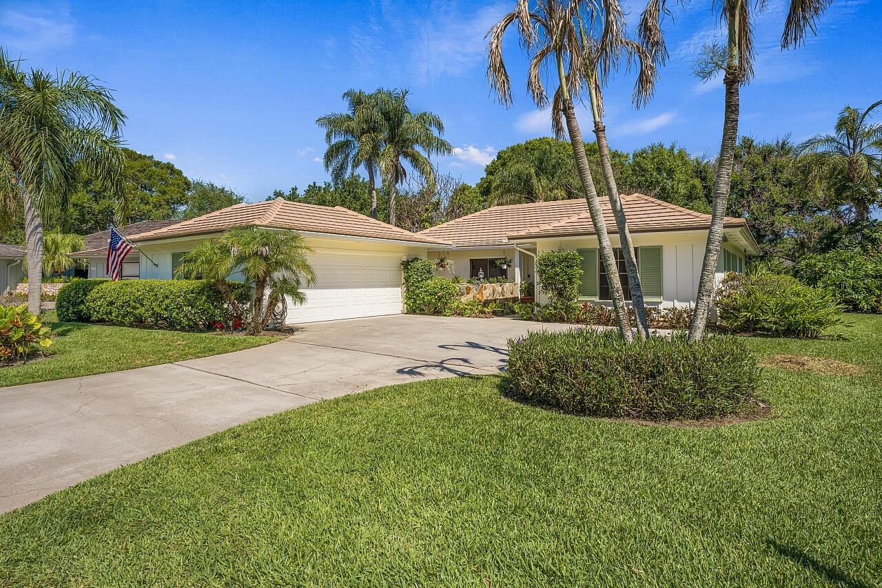 A single-story house with a white garage, tan roof, and palm trees in the yard — VERO BEACH, FL