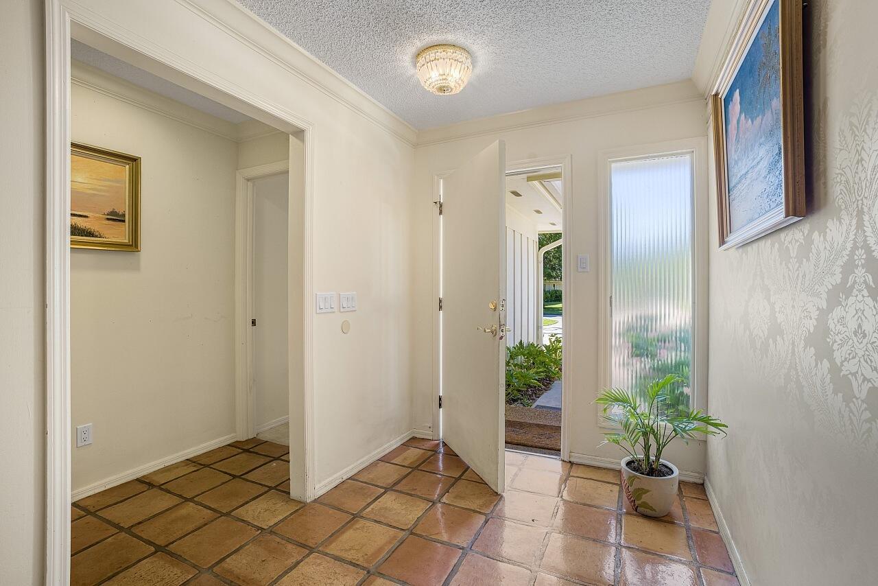 An entryway features terracotta tile flooring, a crystal flush-mount light, and an open front door — VERO BEACH, FL