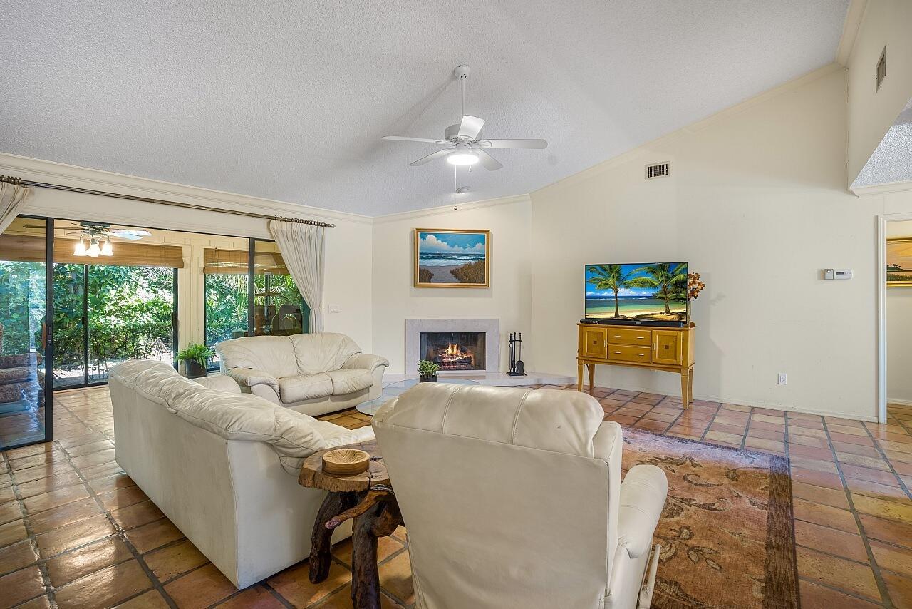 A living room features a vaulted ceiling, tile floors, a fireplace, and a sliding glass door — VERO BEACH, FL