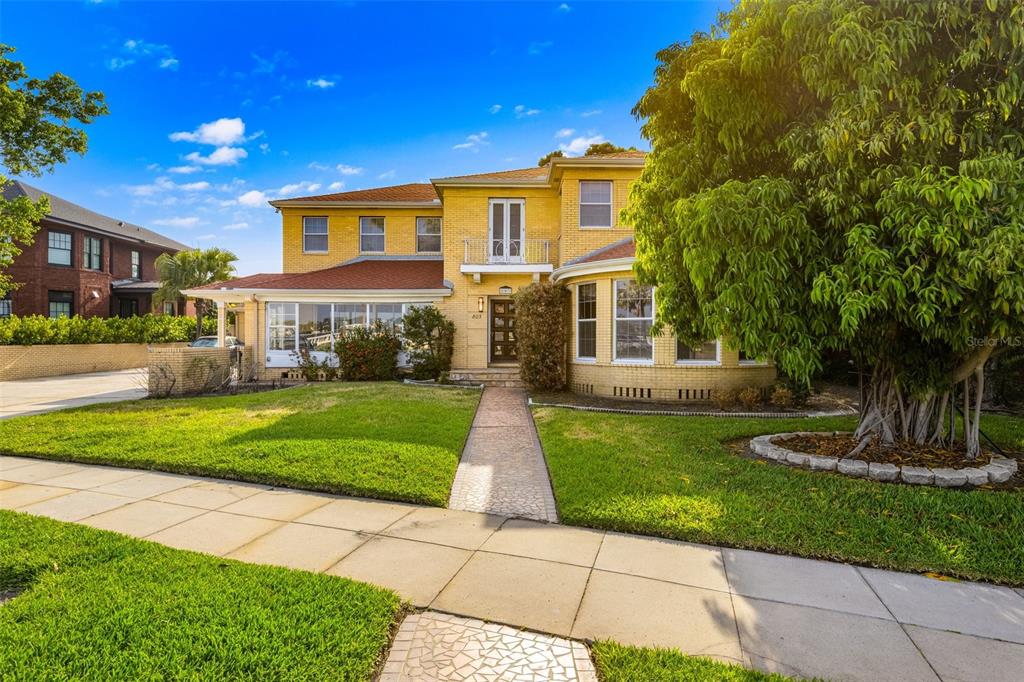 A two-story yellow brick house features a sunroom, a front balcony, and a paved walkway — 803 BAYSHORE BOULEVARD, TAMPA, FL