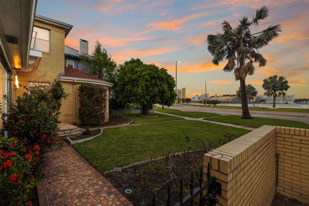 A yellow brick house with a tiled walkway and lawn overlooks a street and city skyline — 803 BAYSHORE BOULEVARD, TAMPA, FL