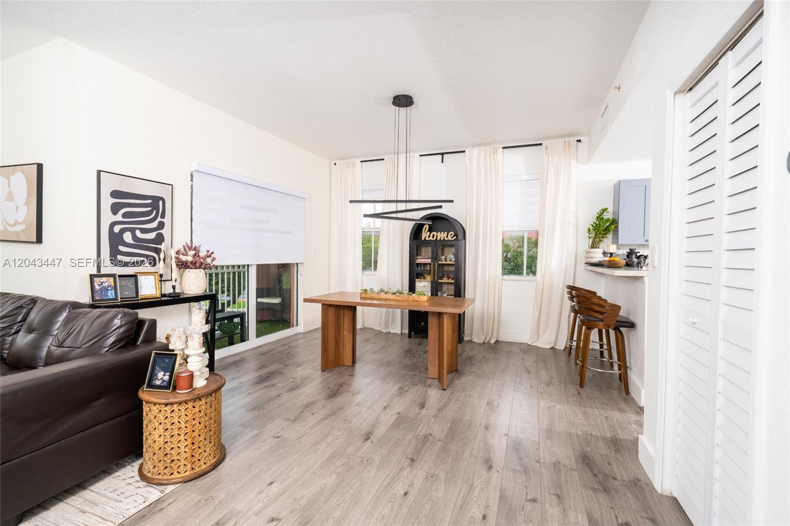This dining area features wood-look flooring, a modern light fixture, and a wooden table — 11101 NW 83rd St # 201, Doral FL 33178, DORAL, FL