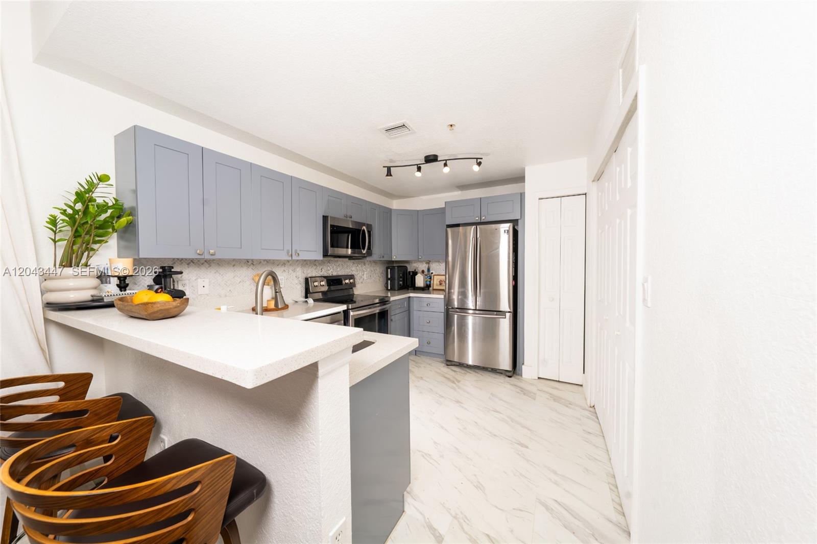 A kitchen features blue cabinets, stainless steel appliances, a breakfast bar, and white marble-look flooring — 11101 NW 83rd St # 201, Doral FL 33178, DORAL, FL