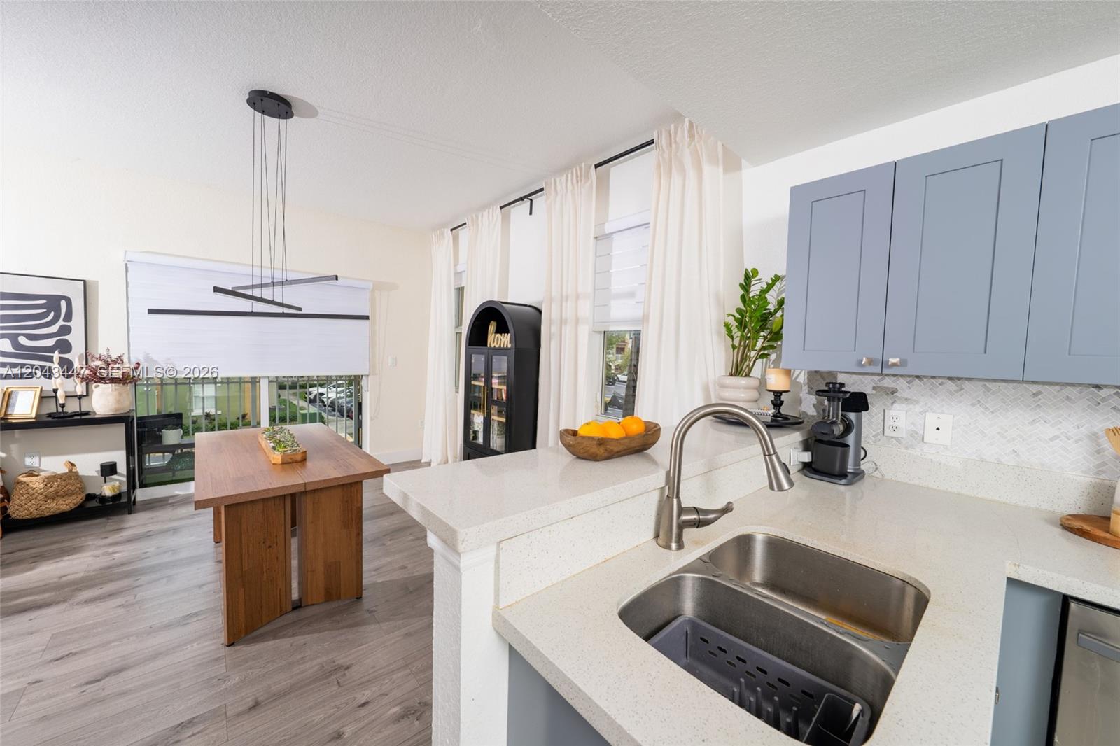 A kitchen with light countertops and blue cabinets overlooks a dining area with wood furniture — 11101 NW 83rd St # 201, Doral FL 33178, DORAL, FL
