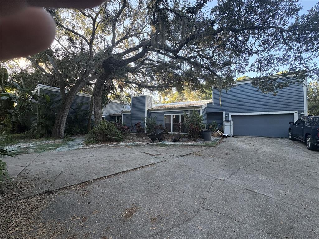 A blue two-story house with a large tree and a cracked concrete driveway — 4889 BRIGITTA DRIVE, SARASOTA, FL