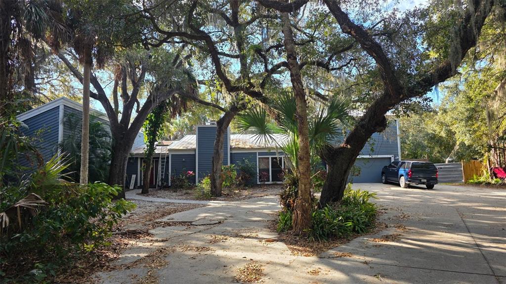 A blue house with a metal roof and a large driveway surrounded by mature trees — 4889 BRIGITTA DRIVE, SARASOTA, FL