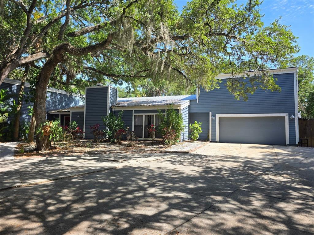 A blue, single-story house with a two-car garage and large oak trees in the front — 4889 BRIGITTA DRIVE, SARASOTA, FL