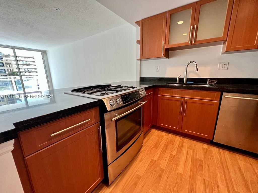 A kitchen features wood cabinets, stainless steel appliances, and black countertops — 2030 S Ocean Dr # 211, Hallandale Beach FL 33009, HALLANDALE BEACH, FL