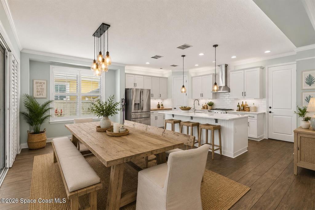 A bright kitchen and dining area features a wooden table, white cabinets, and an island — 10651 LANGEFIELD STREET, ORLANDO, FL