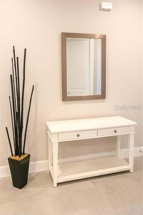 A white console table with two drawers sits below a rectangular mirror on a wall — 7520 SUNVILLE AVENUE, KISSIMMEE, FL
