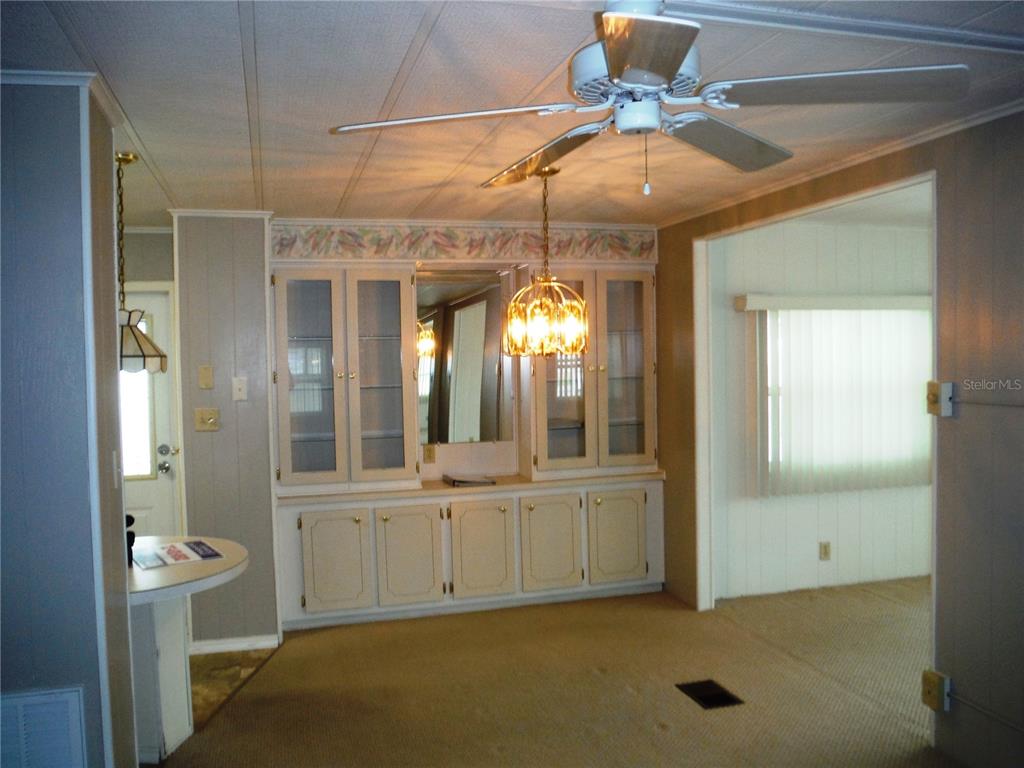 A dining room features a built-in hutch, a ceiling fan, and carpeted flooring — 161 HICKORY GATE DRIVE, PALM HARBOR, FL