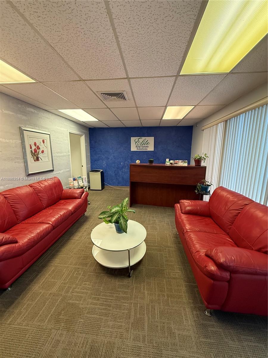 A waiting area features two red leather sofas, a round coffee table, and a reception desk — 8741 NW 57th St, Tamarac FL 33351, TAMARAC, FL