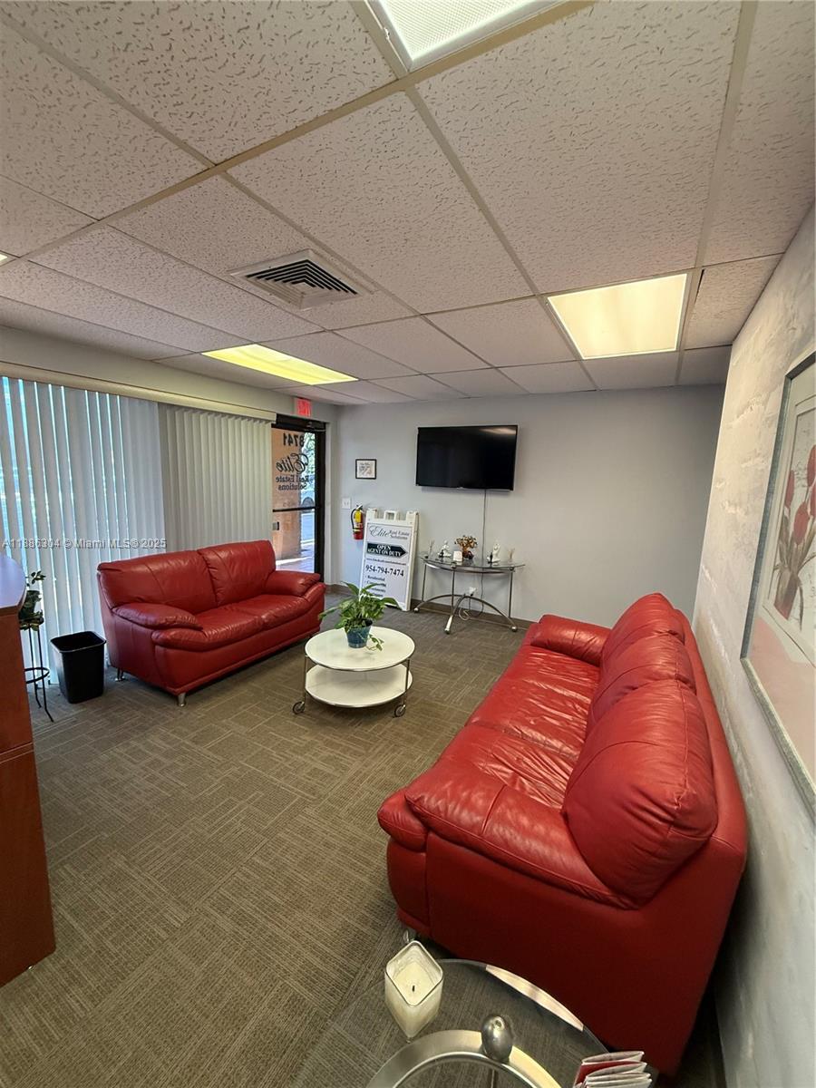 A waiting room features two red leather sofas, a coffee table, and a wall-mounted television — 8741 NW 57th St, Tamarac FL 33351, TAMARAC, FL