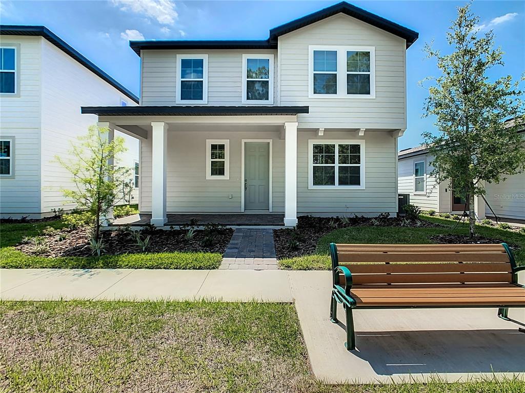 A two-story house with light gray siding, a front porch, and a bench in front — 11165 GREEN CITRON ALLEY, WINTER GARDEN, FL