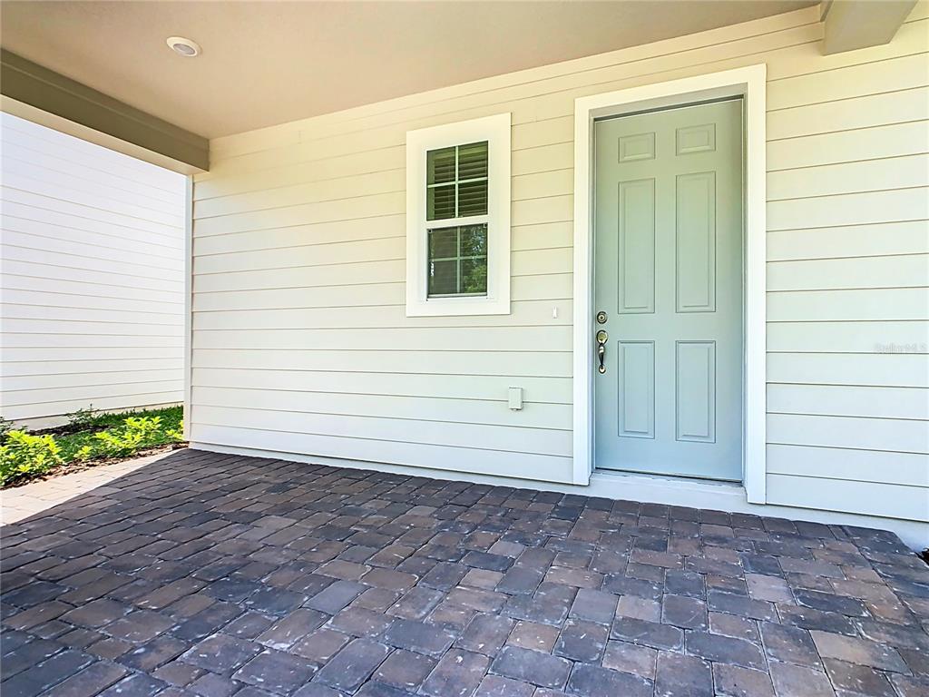 A light blue door and a window are set into the light-colored siding of a porch — 11165 GREEN CITRON ALLEY, WINTER GARDEN, FL