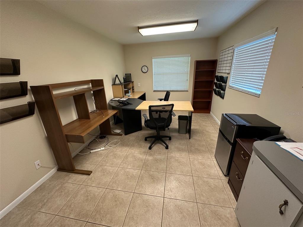 An office room features tile flooring, a large desk, a bookshelf, and two windows — 502 E AIRPORT BOULEVARD, SANFORD, FL
