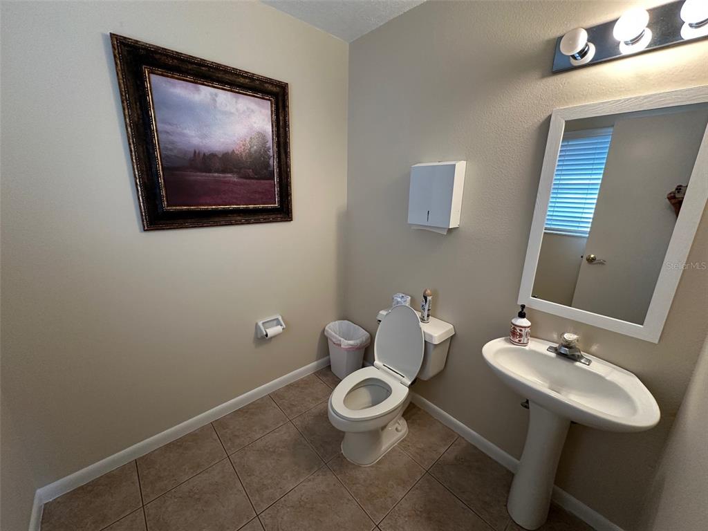 A bathroom features a pedestal sink, a toilet, a wall-mounted paper dispenser, and framed artwork — 502 E AIRPORT BOULEVARD, SANFORD, FL