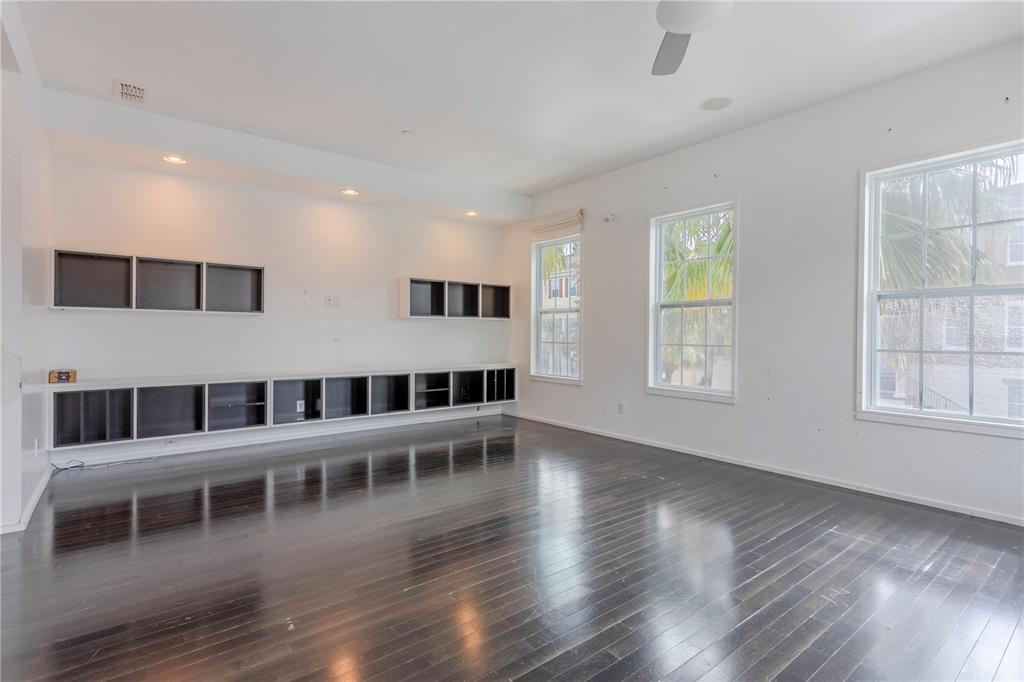 An empty room features dark hardwood floors, white walls, built-in shelving, and three large windows — 2595 JOSLIN PLACE, ORLANDO, FL