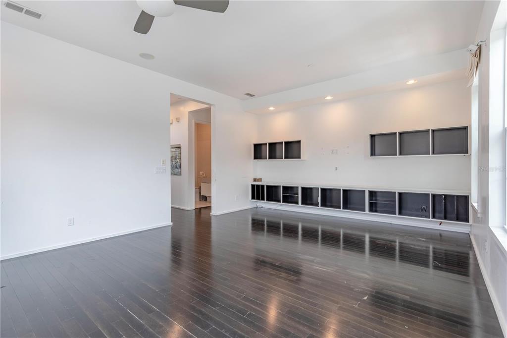 A living room features dark hardwood floors, white walls, and built-in shelving units — 2595 JOSLIN PLACE, ORLANDO, FL