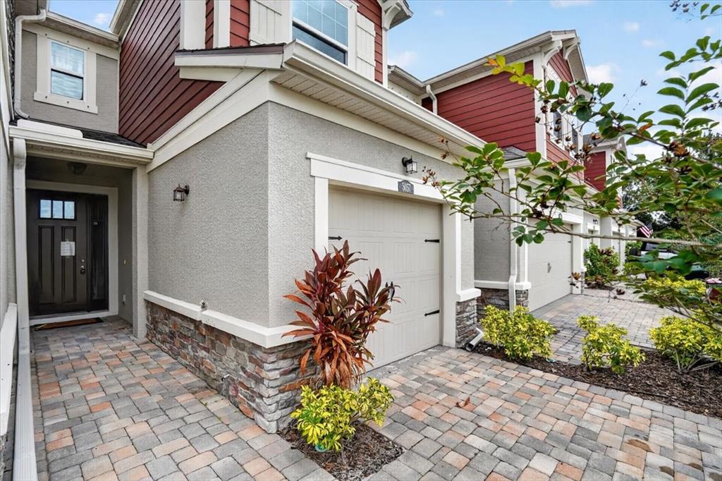 A view of a townhome exterior featuring a paved driveway, garage, and front entrance — 5057 SKYVIEW LANE, BRADENTON, FL