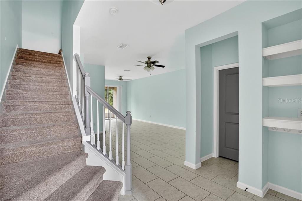 A carpeted staircase leads to an upper level next to a tiled living area — 5057 SKYVIEW LANE, BRADENTON, FL
