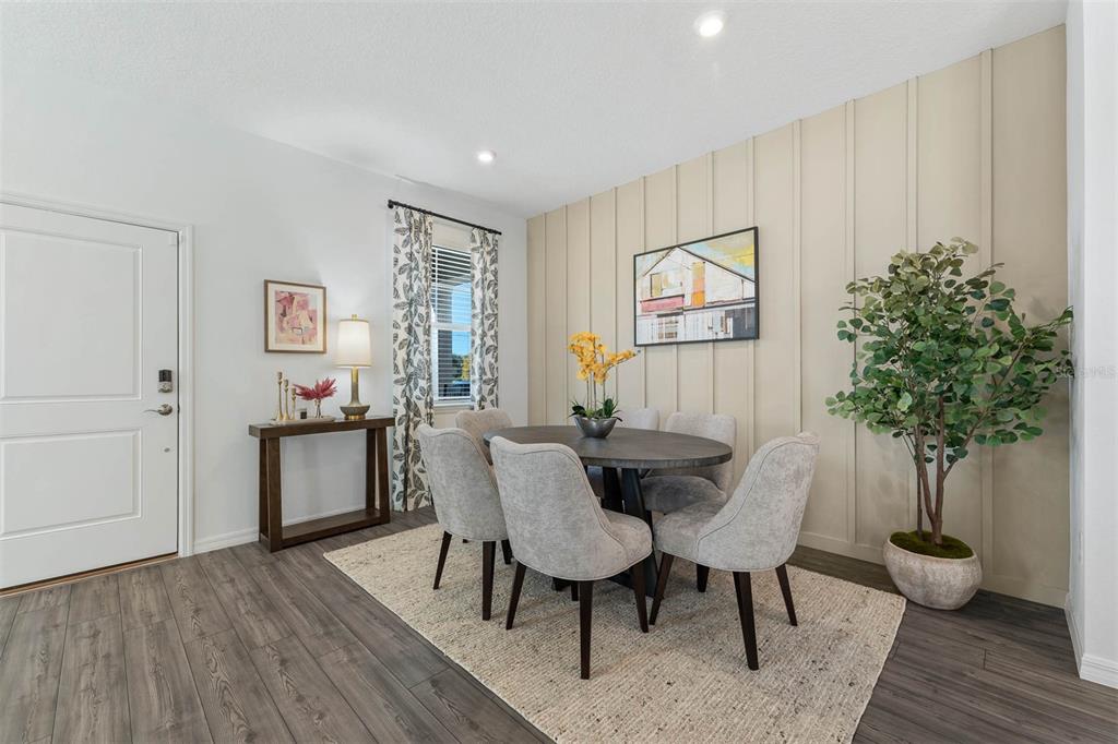 A dining room features a round table, four upholstered chairs, and a vertical paneled accent wall — 1856 SHADOW BOX BEND, ST CLOUD, FL