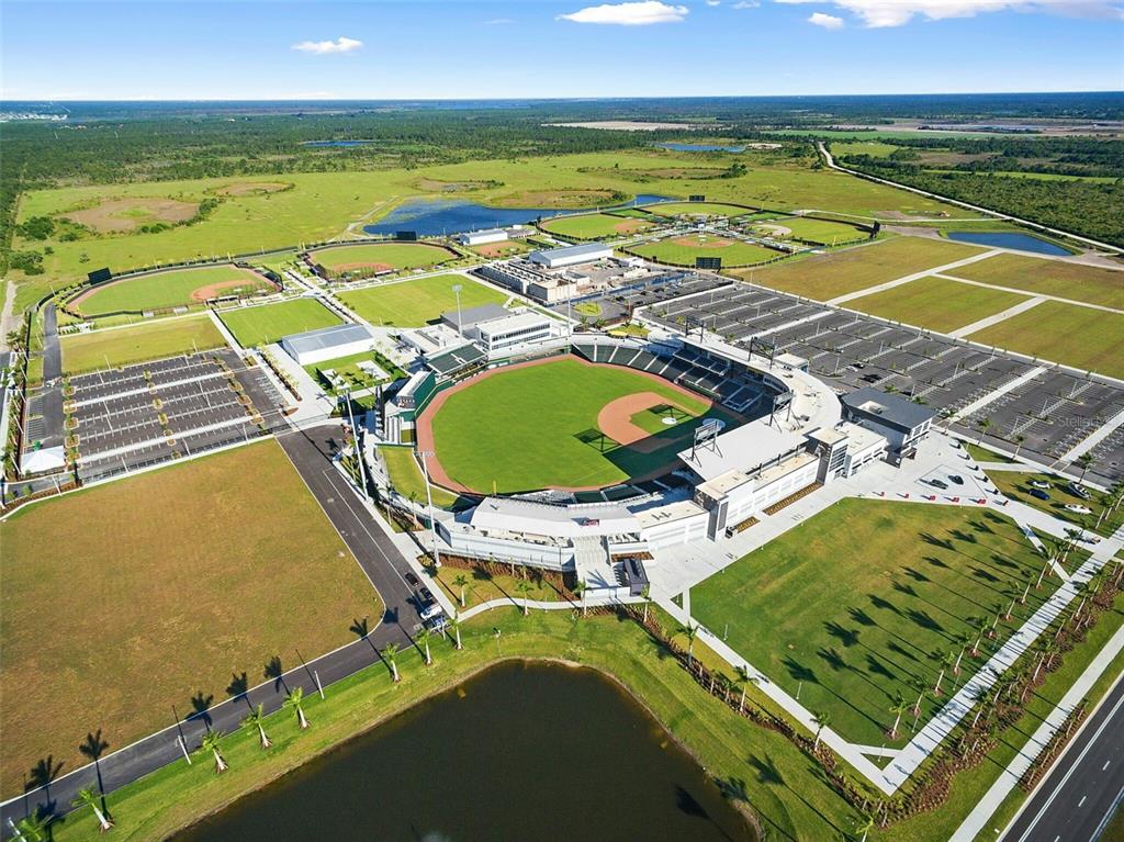 An aerial view shows a baseball stadium complex surrounded by parking lots and open fields — MC GINNIS TERRACE, NORTH PORT, FL