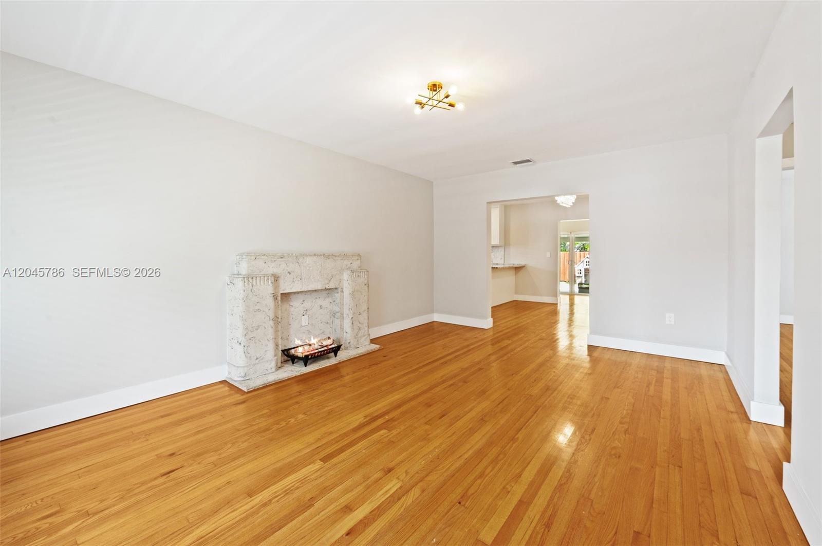 A living room features a marble fireplace, hardwood floors, and an opening to a kitchen — 4355 SW 2nd St, Miami FL 33134, MIAMI, FL