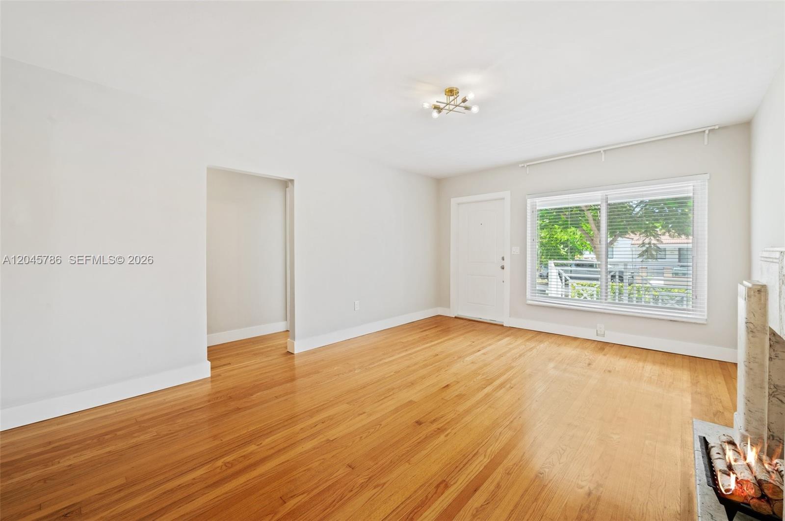 A living room features hardwood floors, a fireplace, a white door, and a large window — 4355 SW 2nd St, Miami FL 33134, MIAMI, FL
