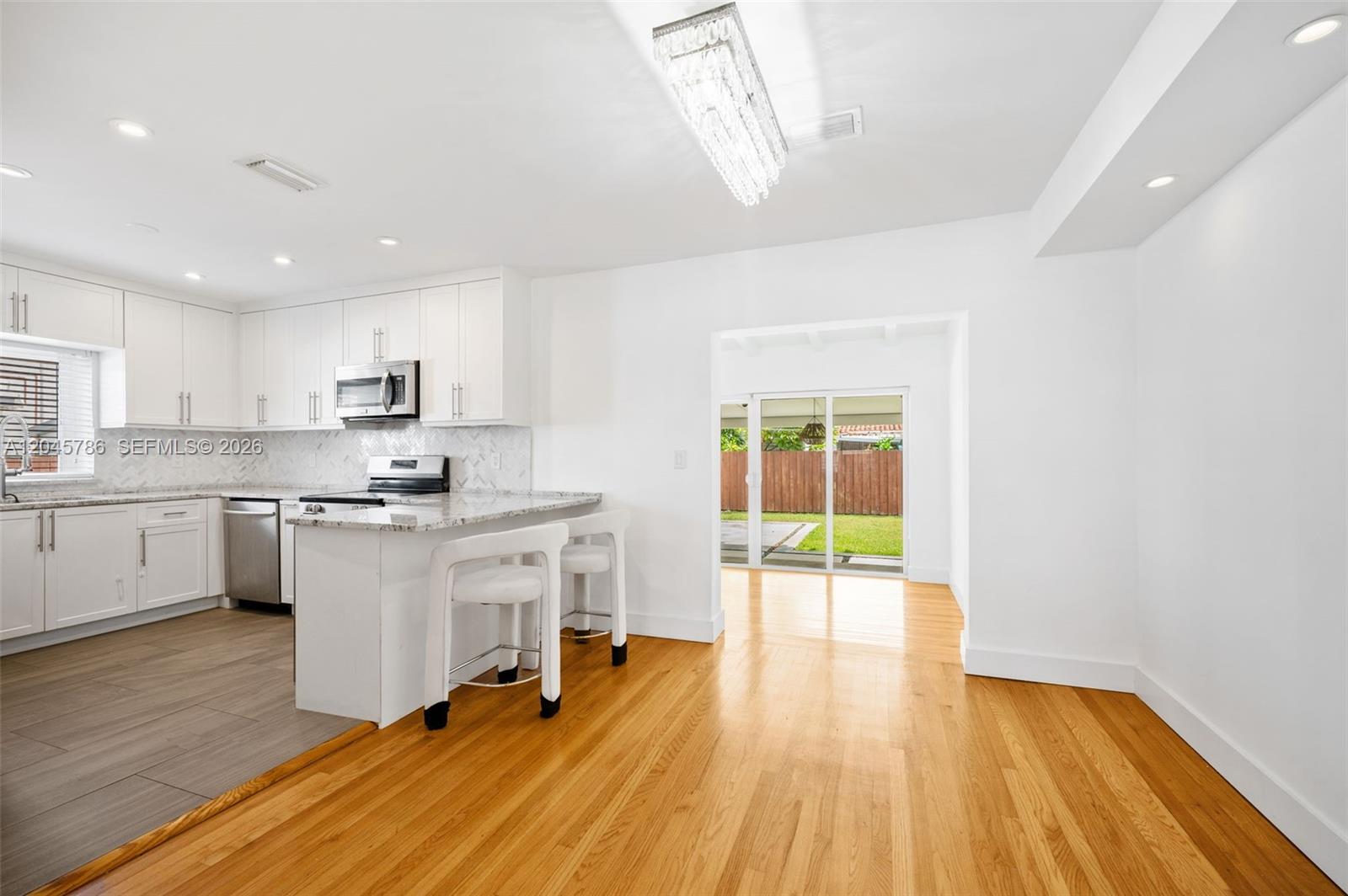 A white kitchen with granite countertops and a breakfast bar opens to a dining area — 4355 SW 2nd St, Miami FL 33134, MIAMI, FL